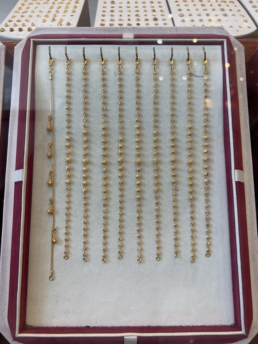 A tray of fine 22ct gold beaded chains on burgundy velvet, Kowaj Jewellers